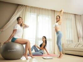 three women doing exercise inside gray room