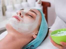 woman lying on blue towel with white cream on face