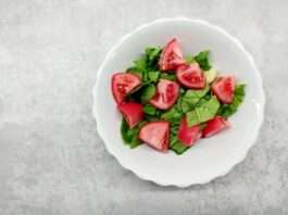 Sliced Tomatoes and Green Leaves in a White Ceramic Bowl